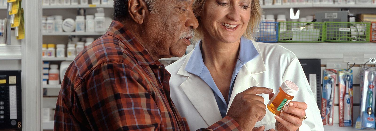 Pharmacist reviewing a prescription bottle with a patient